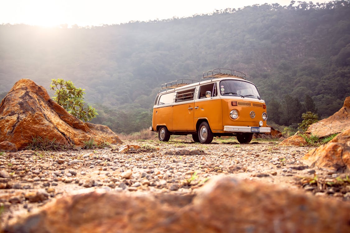 Yellow campervan on dirt at a campground with mountain in the back