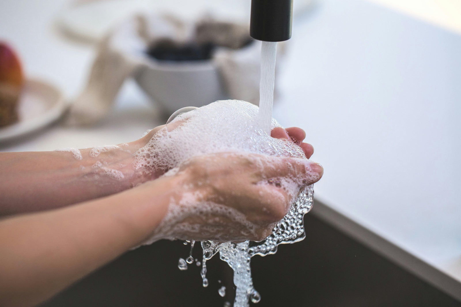 Person washing their hands in soapy water with tap running. Eco-friendly hand soap tablets. Travel-friendly to stay clean anywhere.