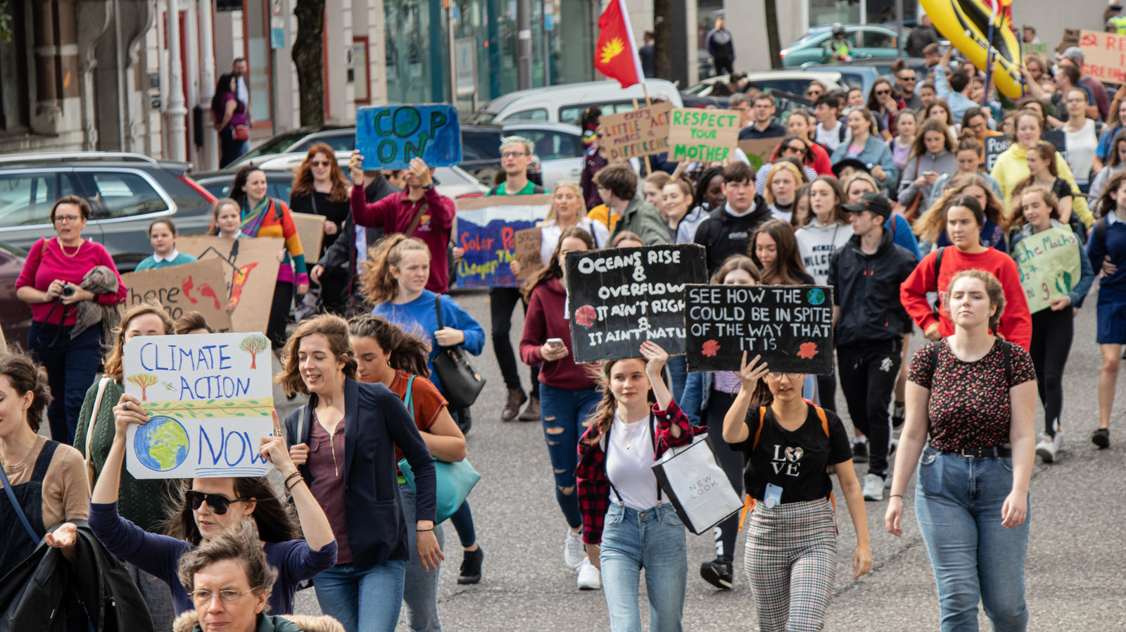 Image of climate change protesters walking with signs for climate justice