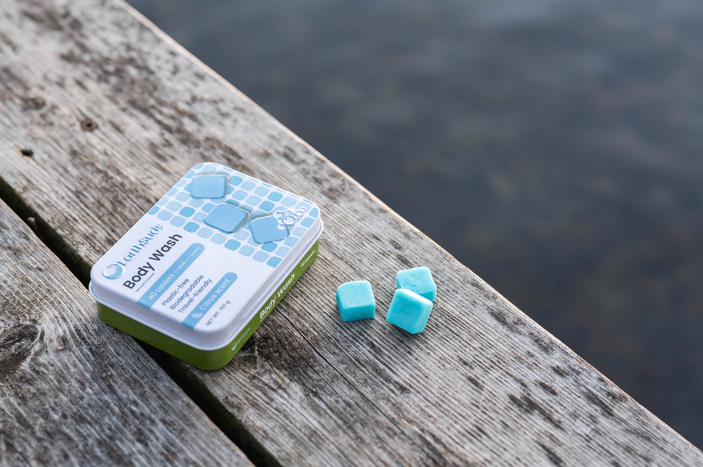 Sustainable shower tablets. Body wash tablets scattered around case by the lake.