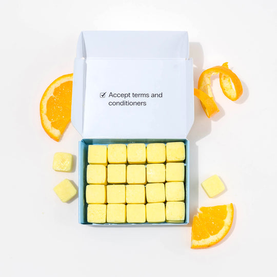 Travel conditioner in box with dissolvable conditioner tablets and oranges around it.