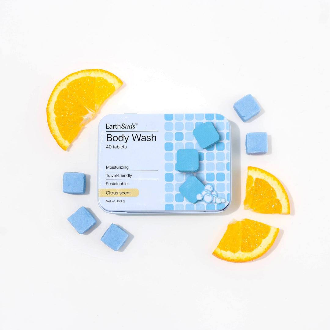 Travel body wash with dissolvable, biodegradable body wash tablets and oranges around it.