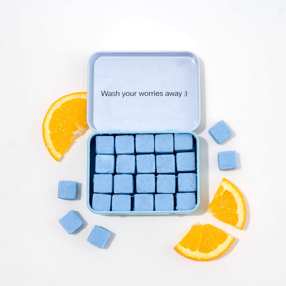 Travel body wash with dissolvable, biodegradable body wash tablets and oranges around it.