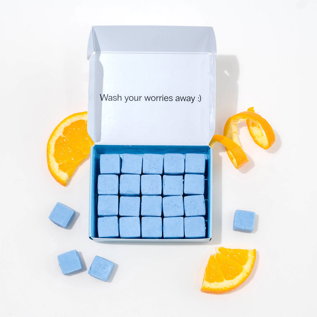 Travel body wash with dissolvable, biodegradable body wash tablets and oranges around it.