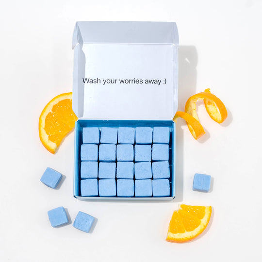 Travel body wash with dissolvable, biodegradable body wash tablets and oranges around it.