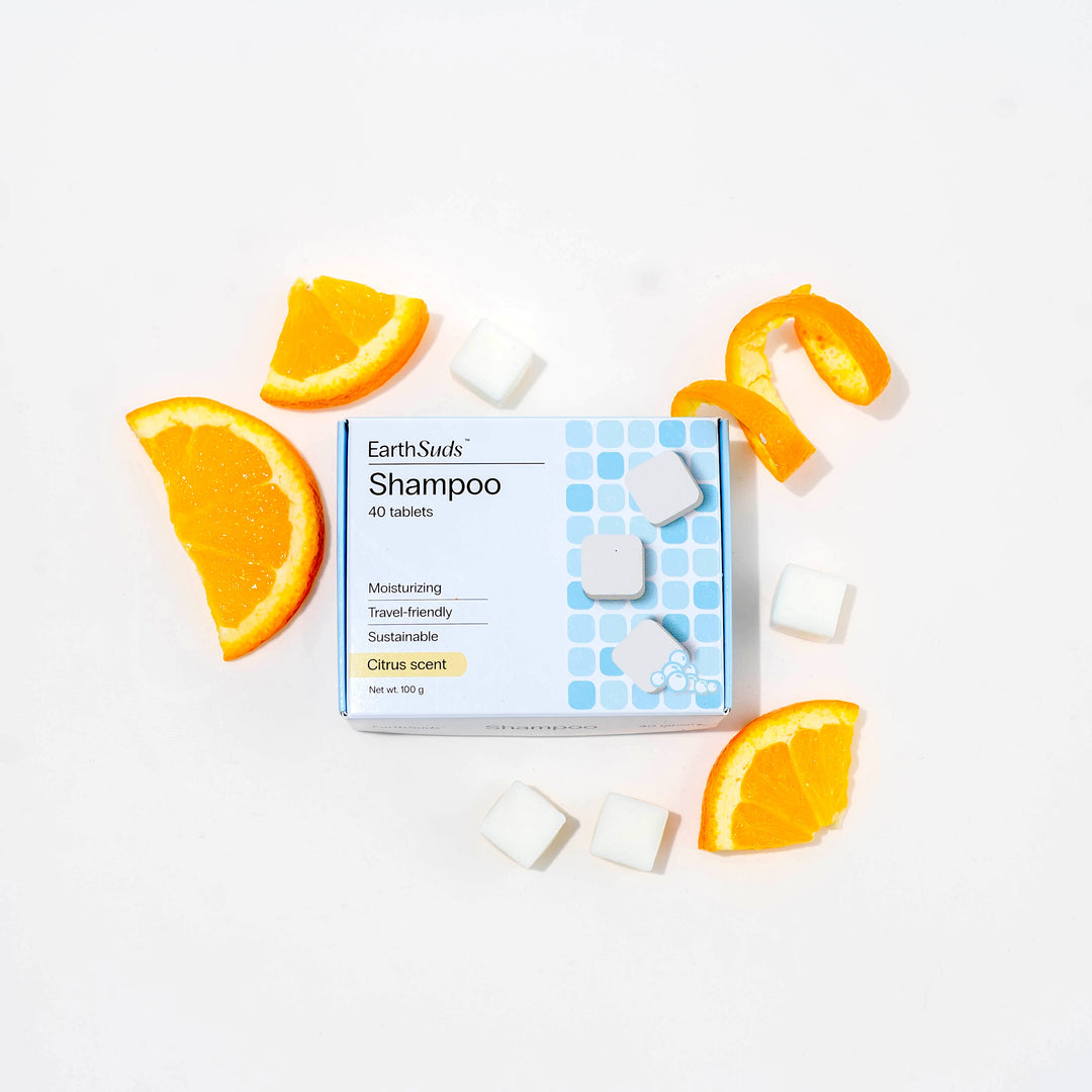 Travel shampoo in box with dissolvable shampoo tablets and oranges around it.