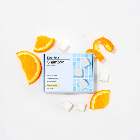 Travel shampoo in box with dissolvable shampoo tablets and oranges around it.