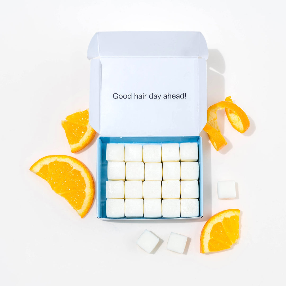Travel shampoo in box with dissolvable shampoo tablets and oranges around it.