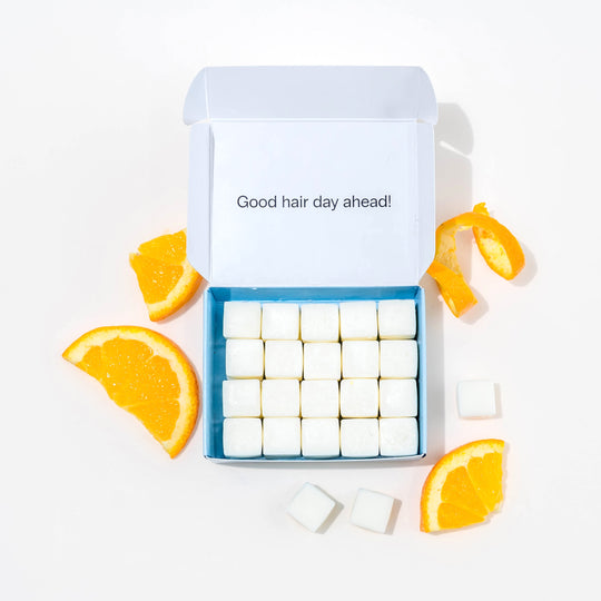 Travel shampoo in box with dissolvable shampoo tablets and oranges around it.