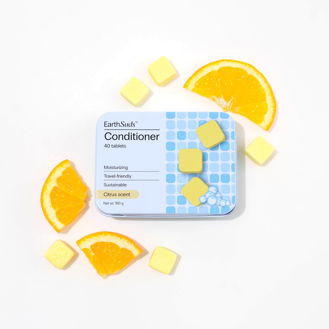 Travel conditioner in case with dissolvable conditioner tablets and oranges around it.