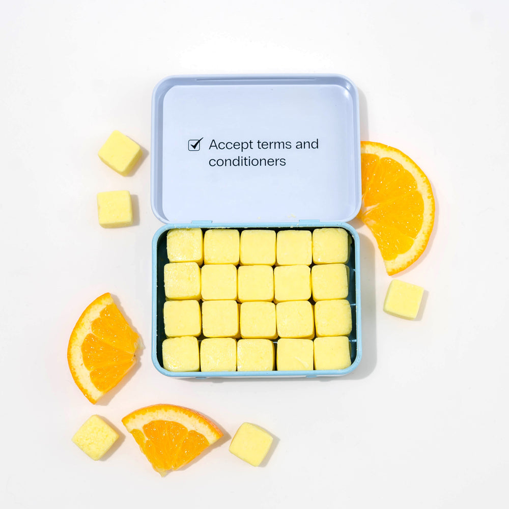 Travel conditioner in case with dissolvable conditioner tablets and oranges around it.
