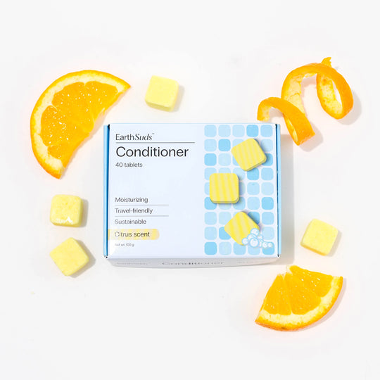 Travel conditioner in box with dissolvable conditioner tablets and oranges around it.
