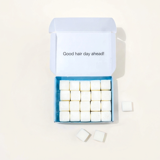 Travel shampoo in box with dissolvable shampoo tablets around it.